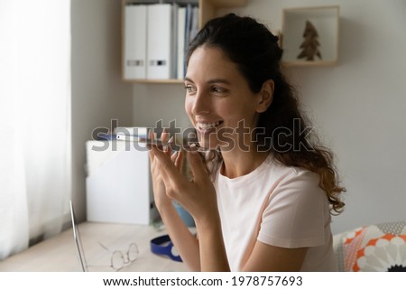 Happy young hispanic latin woman recording audio message on cellphone, sharing good news or discussing life events, holding loudspeaker conversation, using virtual assistant app, distant communication