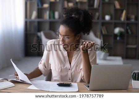 Stressed millennial generation african mixed race woman in eyewear looking at financial documents paper utility bills, feeling nervous about mistakes or bank loan rejection, bankruptcy concept. Royalty-Free Stock Photo #1978757789