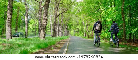 boys on bicycle ride home from school through spring forest in the netherlands near utrecht