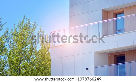 Apartment residential house and home facade architecture and outdoor facilities. Multistoried modern, new and stylish living block of flats. Blue sky on the background. Sunlight in sunrise.