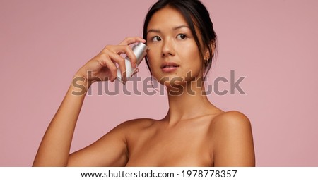 Beautiful asian woman applying skincare serum on her face. Woman using essential oil of her face. Royalty-Free Stock Photo #1978778357