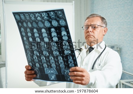 Senior man doctor examines MRI image of human head in hospital