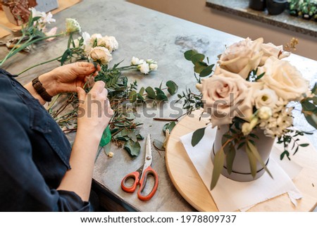 Florist prepares flowers and plants to create an unusual bouquet for the holiday Royalty-Free Stock Photo #1978809737