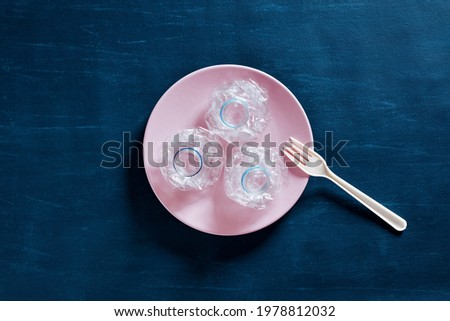 Pressed plastic water bottles on a plate with a plastic fork. Microplastics in food, nutrition, health and environmental pollution or safety concept.