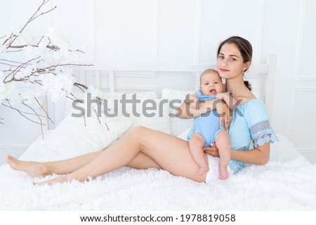 young mom with newborn baby cuddle at home on the bed, happy family and birthday concept