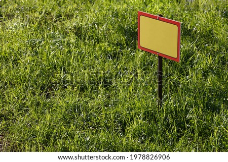 blank yellow sign mockup on green lawn background - close-up with selective focus