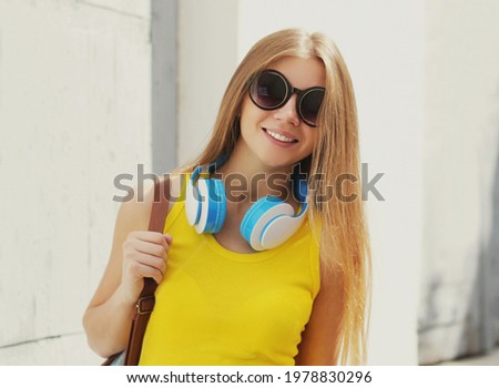 Portrait of smiling young woman with headphones listening to music on in the city