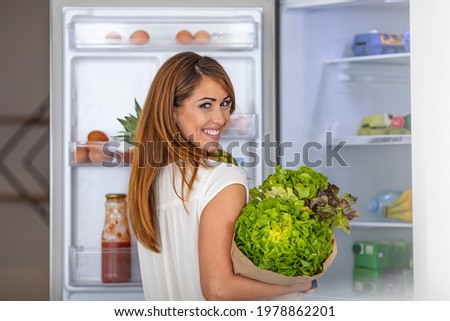 Healthy Eating Concept. Diet. Beautiful Young Woman near the Fridge with healthy food. Fruits and Vegetables in the Refrigerator. Vegan food. Young woman with purchase box full of vegetables 