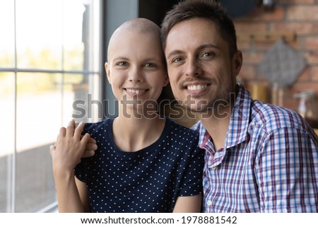 Screen view of happy young married couple hugging, smiling, looking at camera during video call at home. Husband embracing ill hairless wife with oncology disease. Cancer concept, Head shot portrait