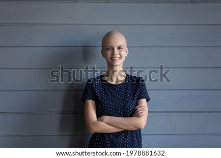 Portrait of happy oncology patient wining fight for life, remission and recovery after successful treatment. Strong confident hairless woman with cancer standing by studio background. Head shot