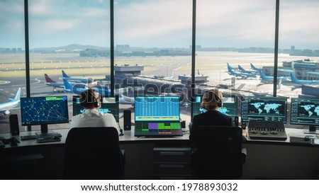 Diverse Air Traffic Control Team Working in a Modern Airport Tower. Office Room is Full of Desktop Computer Displays with Navigation Screens, Airplane Departure and Arrival Data for Controllers. Royalty-Free Stock Photo #1978893032
