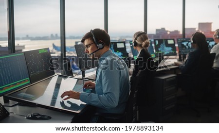 Diverse Air Traffic Control Team Working in a Modern Airport Tower. Office Room is Full of Desktop Computer Displays with Navigation Screens, Airplane Departure and Arrival Data for Controllers. Royalty-Free Stock Photo #1978893134