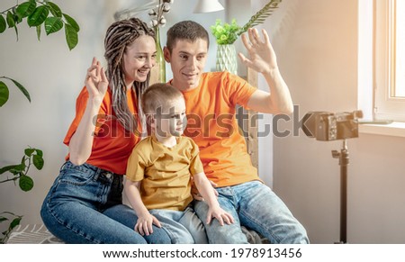 Happy mom, dad and child in bright clothes is posing for the camera and taking photos. Concept of a funny and bright mood, family care, lifestyle.