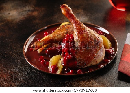 Roasted duck legs with red cranberry sauce and orange wedges. Delicious and healthy food.