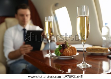 Businessman working at table in airplane during flight, focus on glass of champagne Royalty-Free Stock Photo #1978931645