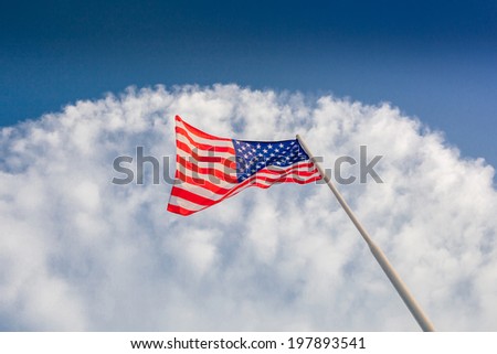 American flag waving with cloudy blue sky, focus on star of waving flag