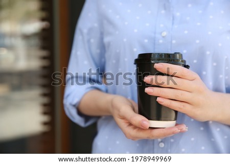 Woman with takeaway coffee cup outdoors, closeup