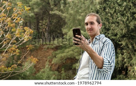 Young handsome man watching a video on his phone outdoor in park