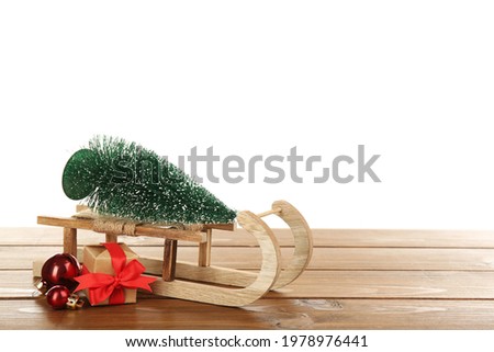 Small sleigh with decorative fir tree, gift box and Christmas balls on wooden table. Space for text