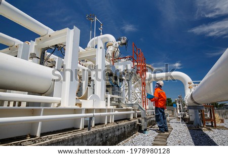 Male worker inspection at steel long pipes and pipe elbow in station oil factory during refinery valve of visual check record pipeline oil and gas industry Royalty-Free Stock Photo #1978980128