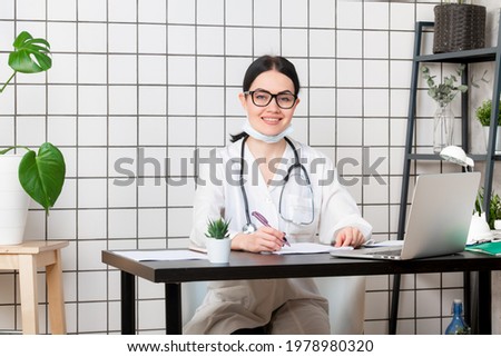 Doctor wearing medical mask at desk at office looking at camera