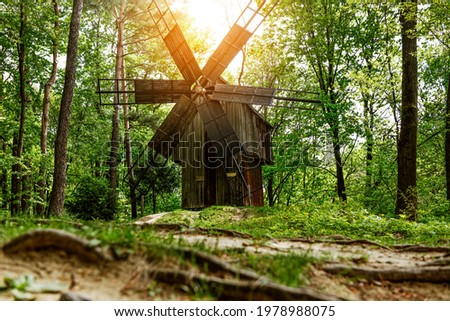An old wooden mill. The foreground is blurred. Sunrise. Forest.