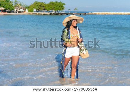Woman holding a pineapple while walking on the beach