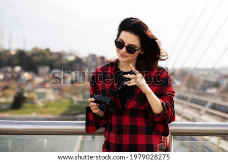Young woman tourist standing with photo camera on the bridge. Beautiful woman traveling around the city