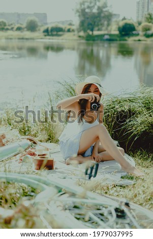 Beautiful young woman takes pictures using camera at picnic. Lifestyle, outdoor recreation on weekends