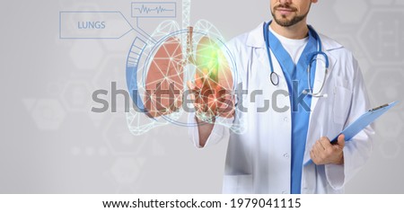Male doctor using virtual screen with picture of lungs on light background