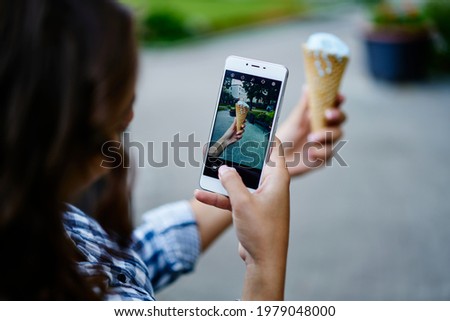 Unrecognizable female tourist clicking photo images of gelato ice cream using cellphone camera during summer vacations, selective focus on mobile screen with displayed sober dessert in scoop