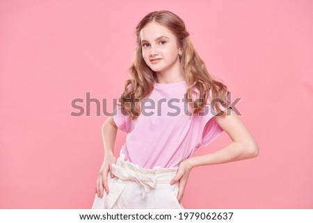 Portrait of a cute teenage girl smiling at camera on a pink background. Youth fashion.