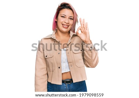 Hispanic woman with pink hair wearing casual clothes smiling positive doing ok sign with hand and fingers. successful expression. 
