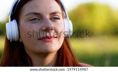 Beautiful girl relaxing listening music or podcast with headphones while walking in the street