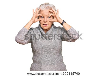 Senior grey-haired woman wearing casual winter sweater trying to open eyes with fingers, sleepy and tired for morning fatigue 