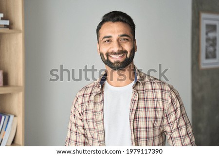 Headshot portrait of attractive confident indian Hispanic man with toothy smile looking at camera at modern living room. Latin businessman posing in casual stylish look at home office. Royalty-Free Stock Photo #1979117390