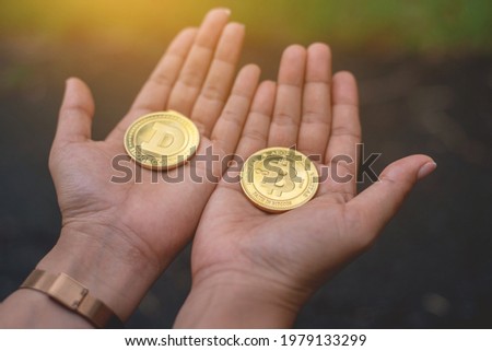 Woman's hand holding Bitcoin and Doge Cryptocurrency.