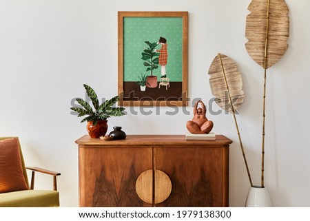 Minimalist composition of living room with brown mock up picture frame, plant, retro armchair, dried tropical leaf, decoration and elegant personal accessories in stylish home decor. Template.