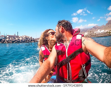 Cheerful pretty man and woman together on a jet sky having fun in summer holiday vacation - travel and happy lifestyle young people - selfie picture and smiles - blue ocean and coastline