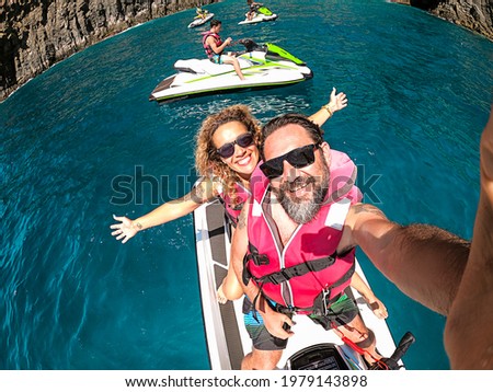 Happy adult couple have fun on jet sky activity escursion in summer holiday vacation at the sea - ocean active people take selfie picture and smile with happiness and freedom - cheerful lifestyle