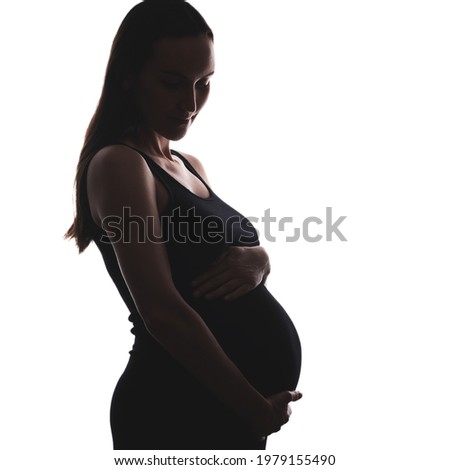 silhouette portrait of pregnant woman in black dress with hand on belly on white background