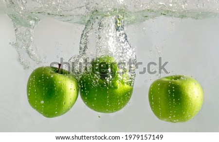 Three green apples falling into water 