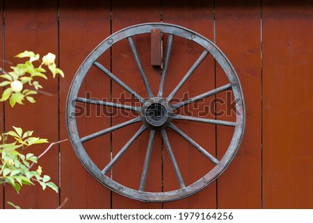 Wheel from a horse carriage hanging on a red wooden wall. Shot in Sweden, Scandinavia