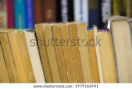 Row of many old used books displayed at local antiquarian bookshop, shallow depth of field photo, only few pages in focus