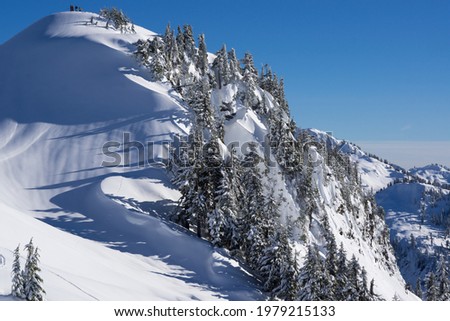 A group of people on top of a mountain covered with a smooth layer of snow. 