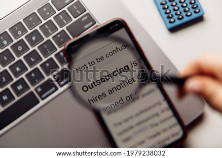 Outsourcing word on phone's screen and magnifying glass