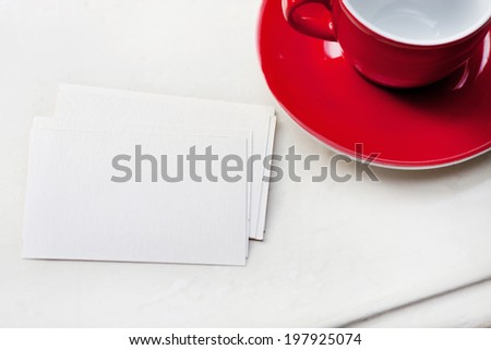 Business card on white table next to red coffee mug and plate