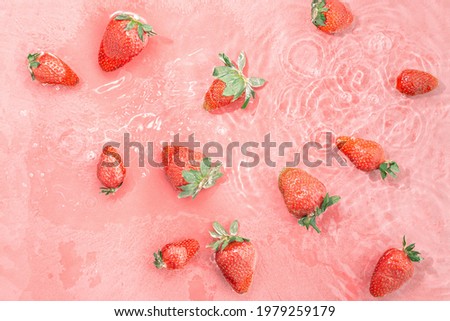 Red strawberries floating on pastel pink water. Idea of healthy fruit dessert. Spring or summer natural food background. Minimal flat lay. Creative pattern. Refreshment concept. Source of vitamin C. Royalty-Free Stock Photo #1979259179