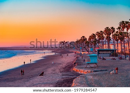 People sit and stroll at sunset on the beach in Oceanside, California. This is next to Carlsbad and San Diego.