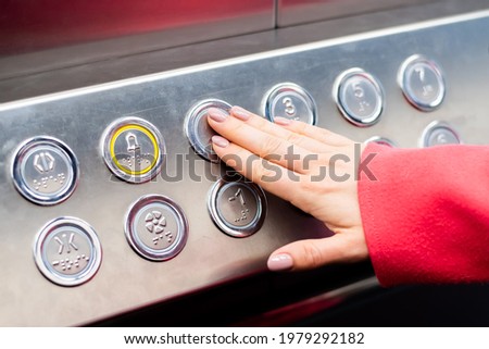 Woman pushing a Button in the elevator with Braille code for blind people